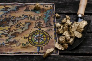 A map of Alaska with nuggets of gold, both of which are on a brown table.
